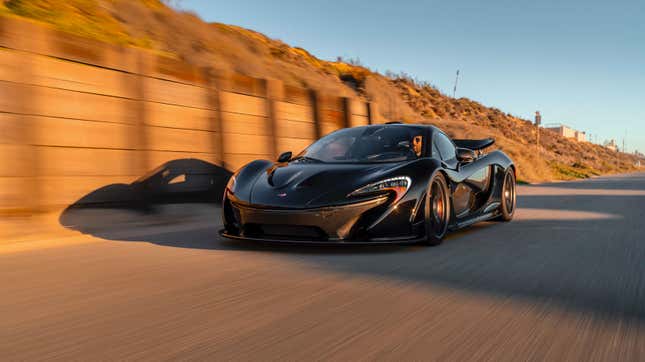 A black McLaren P1 hypercar driving at sunset 